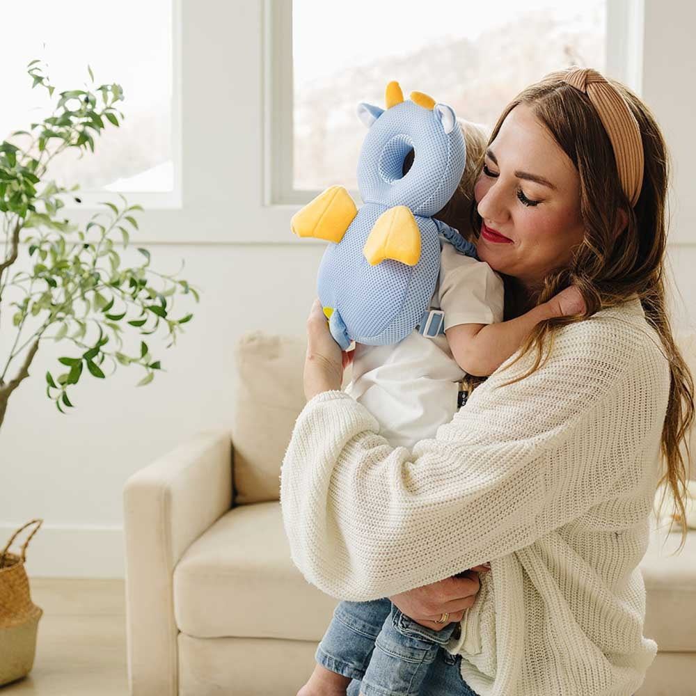 Mother hugging her toddler who wears the blue dragon head protector