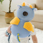 Toddler sitting on a play mat wearing the blue dragon head protector backpack