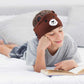 Boy reading on the bed wearing brown bear headband headphones