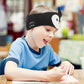 Boy drawing at the table while listening on penguin headband headphones
