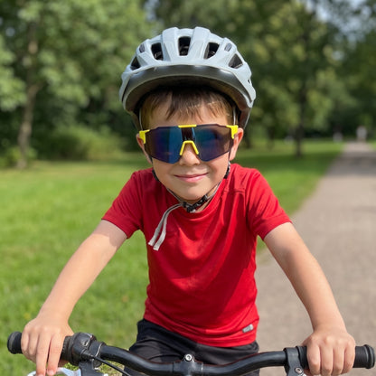 Boy on a bike wearing yellow kids sports sunglasses with a blue mirrored lens
