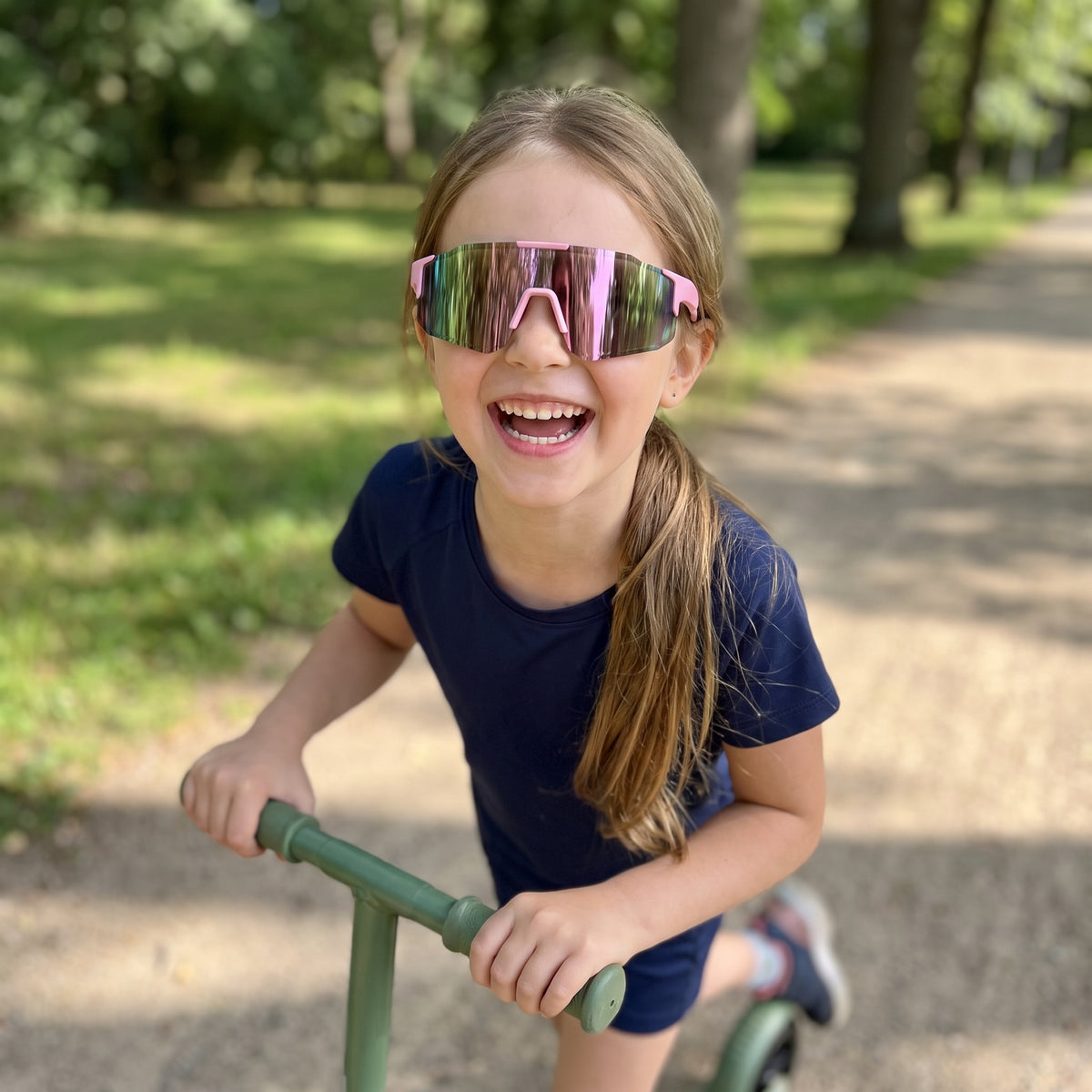 Girl on a scooter wearing pink kids sports sunglasses