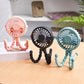 Pink, black and blue pram fans standing on a table