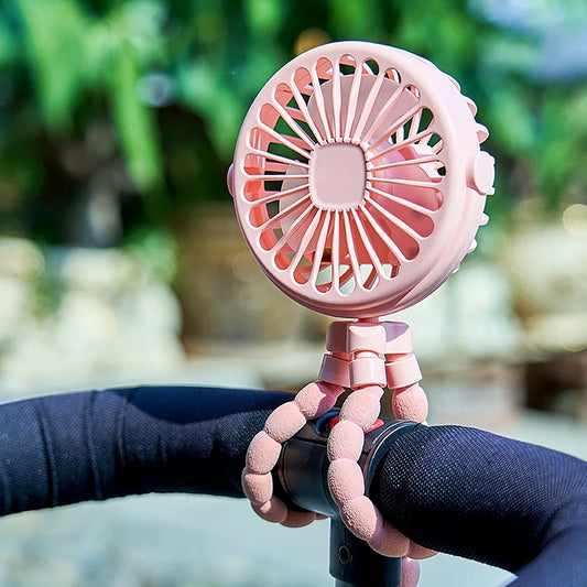 Pink pram fan wrapped round a pushchair handle in the park