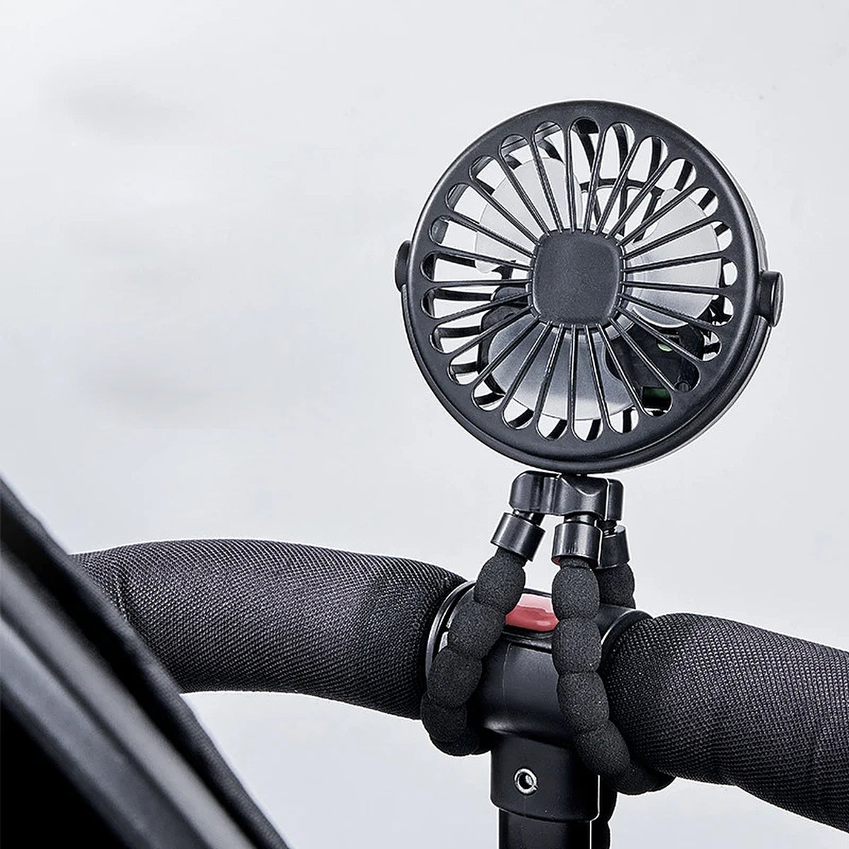 Black pram fan clipped to a pushchair handlebar